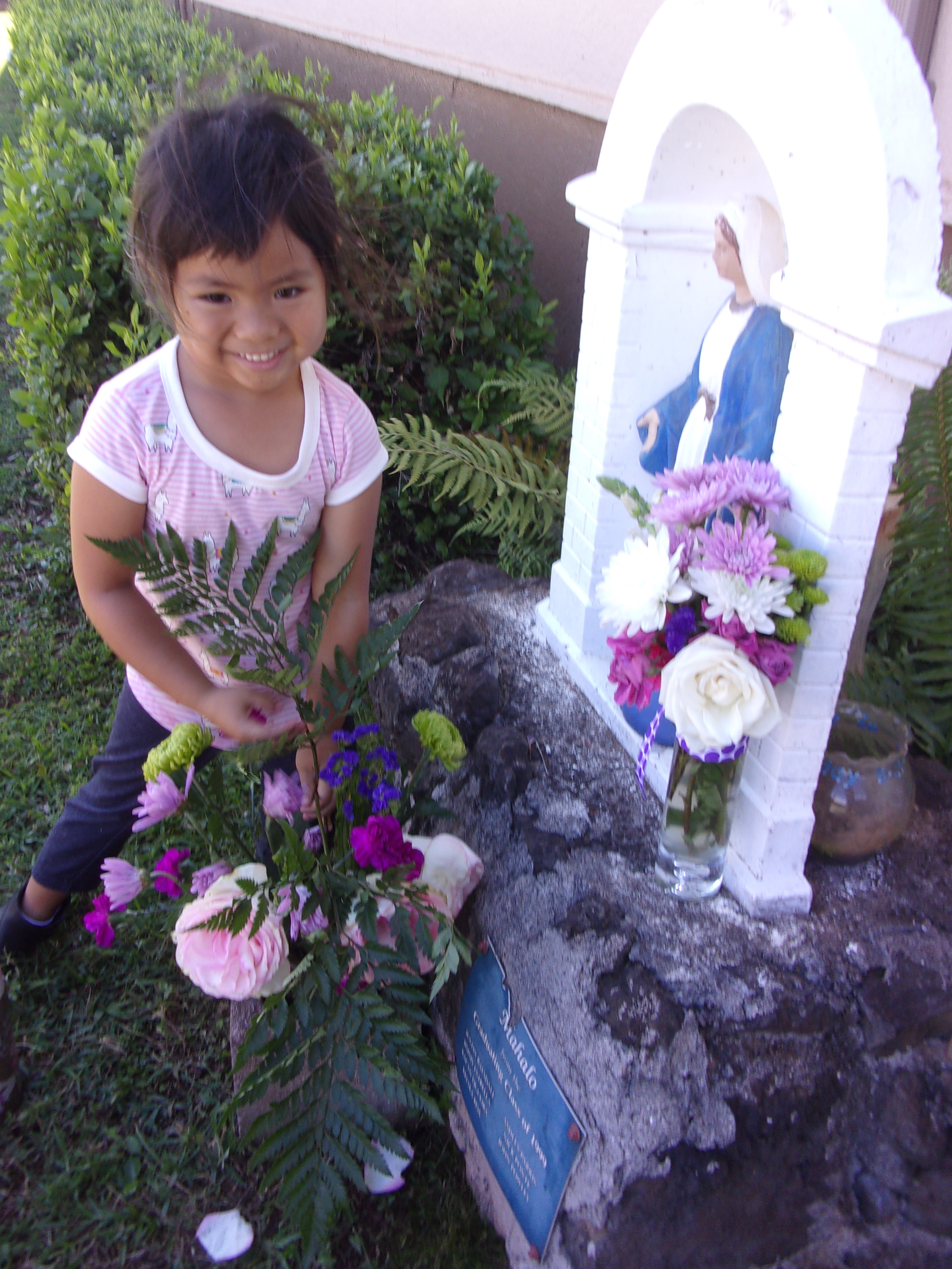 Student Preesenting Flowers to Statue of Mary